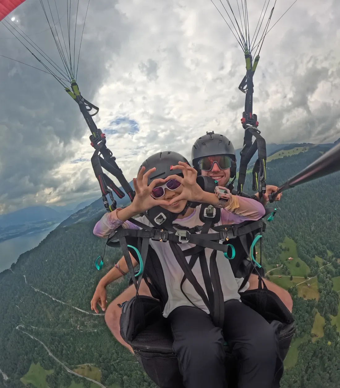 Two smiling people during a tandem paragliding flight in Valais.